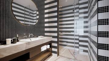A modern bathroom with a large mirror, two sinks, and a glass shower enclosure.