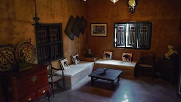 A traditional room with a sofa, a wooden cabinet, a small table, and a window with a view.