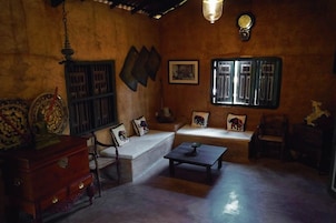 Una habitación tradicional con sofá, un aparador de madera, una mesita y una ventana con vistas.