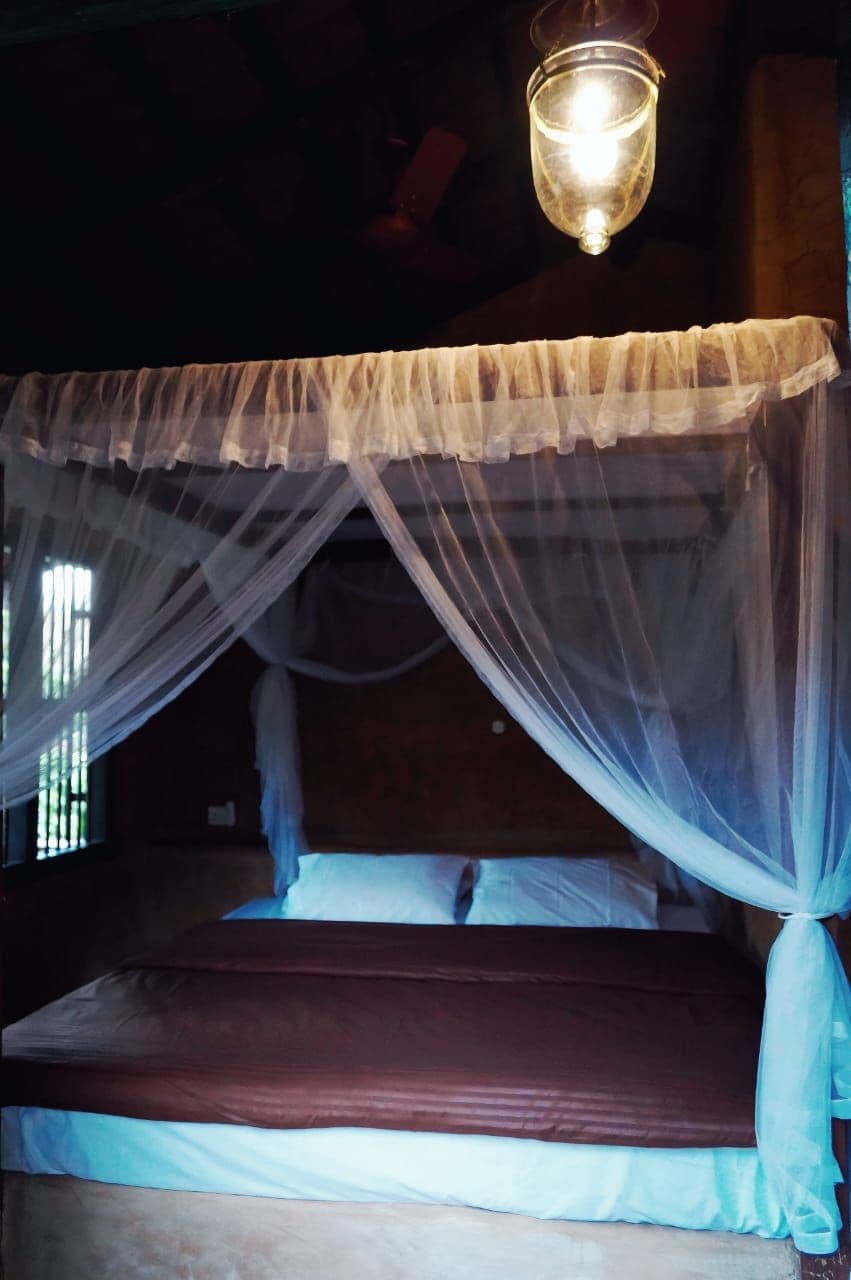Un lit à baldaquin avec une suspension lumineuse au-dessus.
