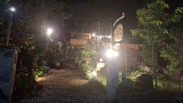 A stone pathway leading to a building with a signboard, surrounded by greenery and illuminated by streetlights. - Mati Gedara Resort (Digana)