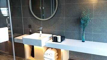 A modern bathroom with a large round mirror, a white sink, and a towel rack.