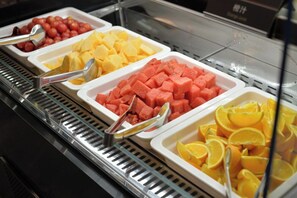 Un bufé con diversas frutas y un piano al fondo.