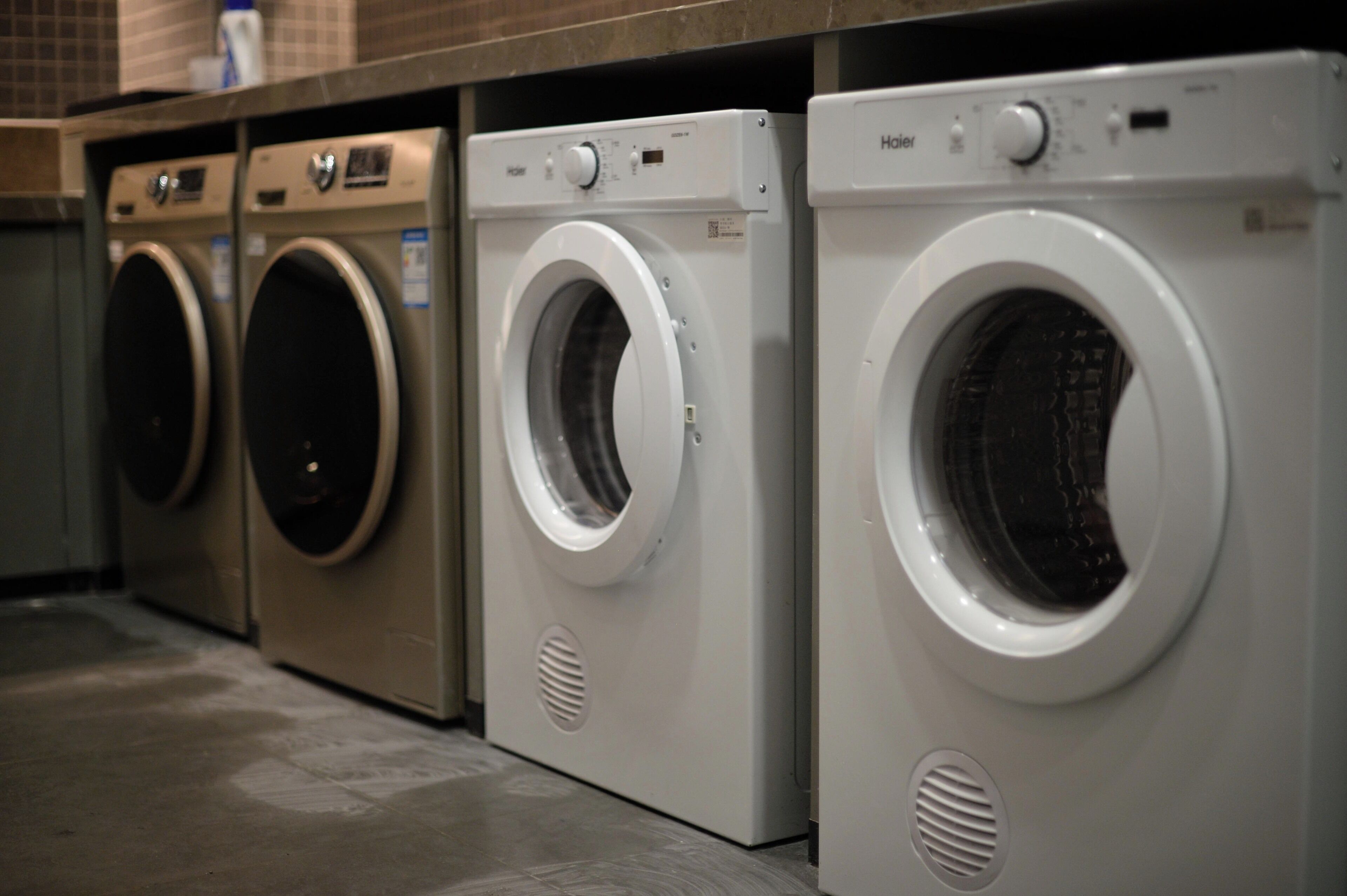 A row of front-loading washing machines in a commercial setting.