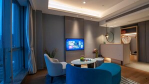A modern hotel room with a large window, a flat-screen TV mounted on the wall, a round table with chairs, and a built-in wardrobe with a mirror. - DeXin JunTing Hotel Wenzhou South (Wenzhou)