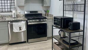 A modern kitchen with stainless steel appliances, a wooden floor, and a metal rack with plants. - Charming 2-bedroom house in El Centro with WiFi, AC (El Centro)