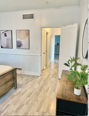 A modern interior with a wooden floor, white walls, and a hallway leading to a kitchen area. - Charming 2-bedroom house in El Centro with WiFi, AC (El Centro)