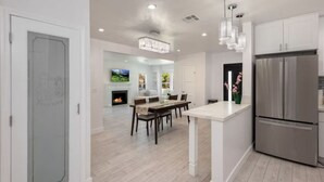 A modern kitchen with a large stainless steel refrigerator, a dining area with a wooden table and chairs, and a fireplace. - Charming 3Bed 2Bath Home with WiFi & AC in enjoyable Beverlywood and BH adjacent (Los Angeles)