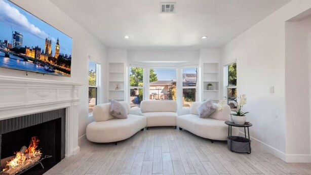 A modern living room with a fireplace, a large flat-screen TV, and a view of the cityscape. - Charming 3Bed 2Bath Home with WiFi & AC in enjoyable Beverlywood and BH adjacent (Los Angeles)
