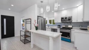 A modern kitchen with white cabinetry, stainless steel appliances, and pendant lighting. - Charming 3Bed 2Bath Home with WiFi & AC in enjoyable Beverlywood and BH adjacent (Los Angeles)