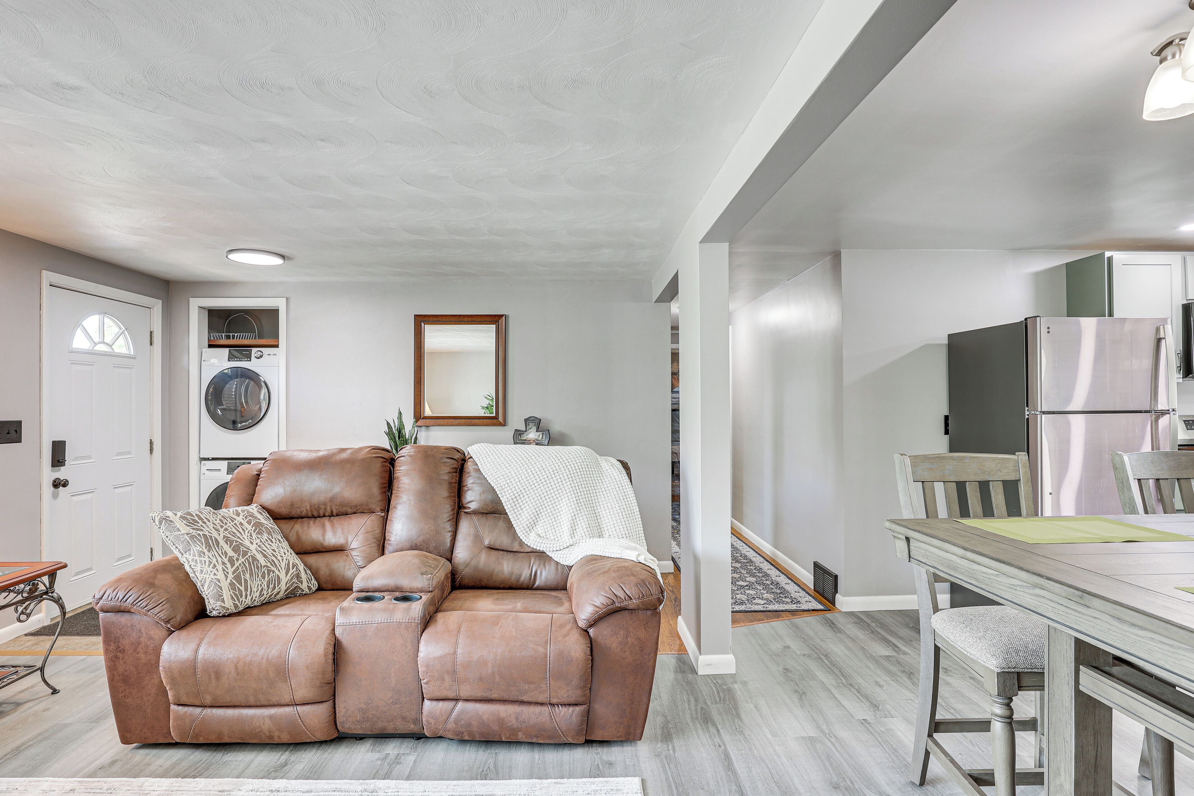 Un salon moderne avec un fauteuil inclinable en cuir, une table à manger et un coin cuisine à l’arrière-plan.