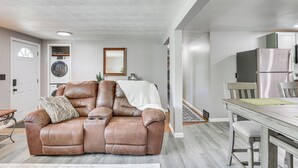 A modern living room with a leather recliner, a dining table, and a kitchen area in the background. - Fish, Hike & Golf: Leisurely Navarre Home w/ Yard! (Navarre)