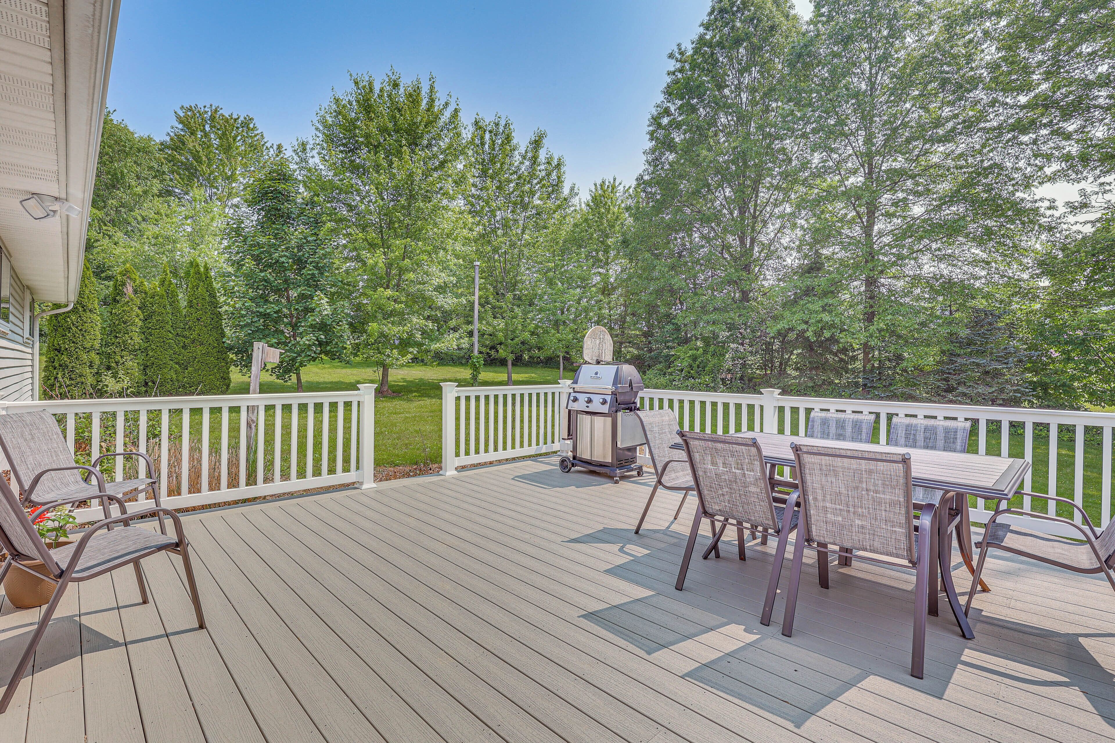 Une terrasse avec un barbecue, des chaises et une table.