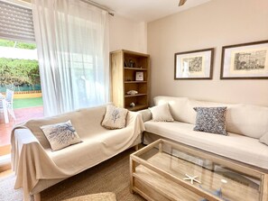 Ein Wohnzimmer mit zwei Sofas, einem Glastisch und einem Bücherregal aus Holz.