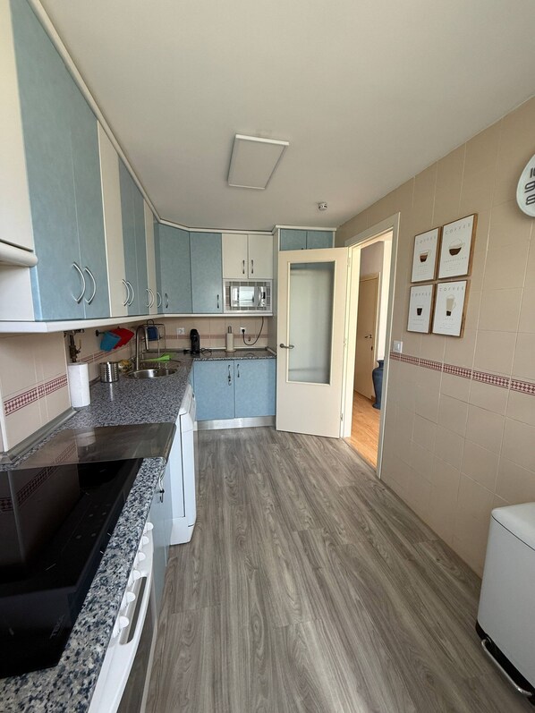 Una cocina con microondas, armarios y un lavabo.