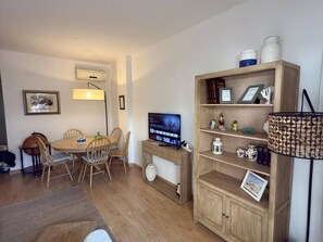 Ein kompakter Wohnbereich mit Essplatz, Fernseher und Bücherregal.