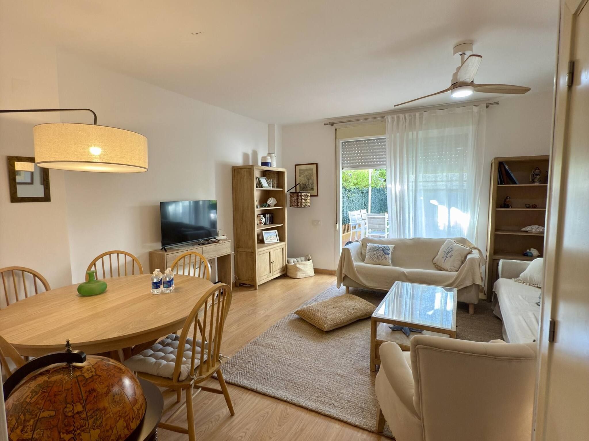 A well-lit living room with a television, dining table, and seating area.