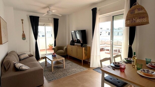 A living room with a sofa, coffee table, TV, and dining area with table and chairs.