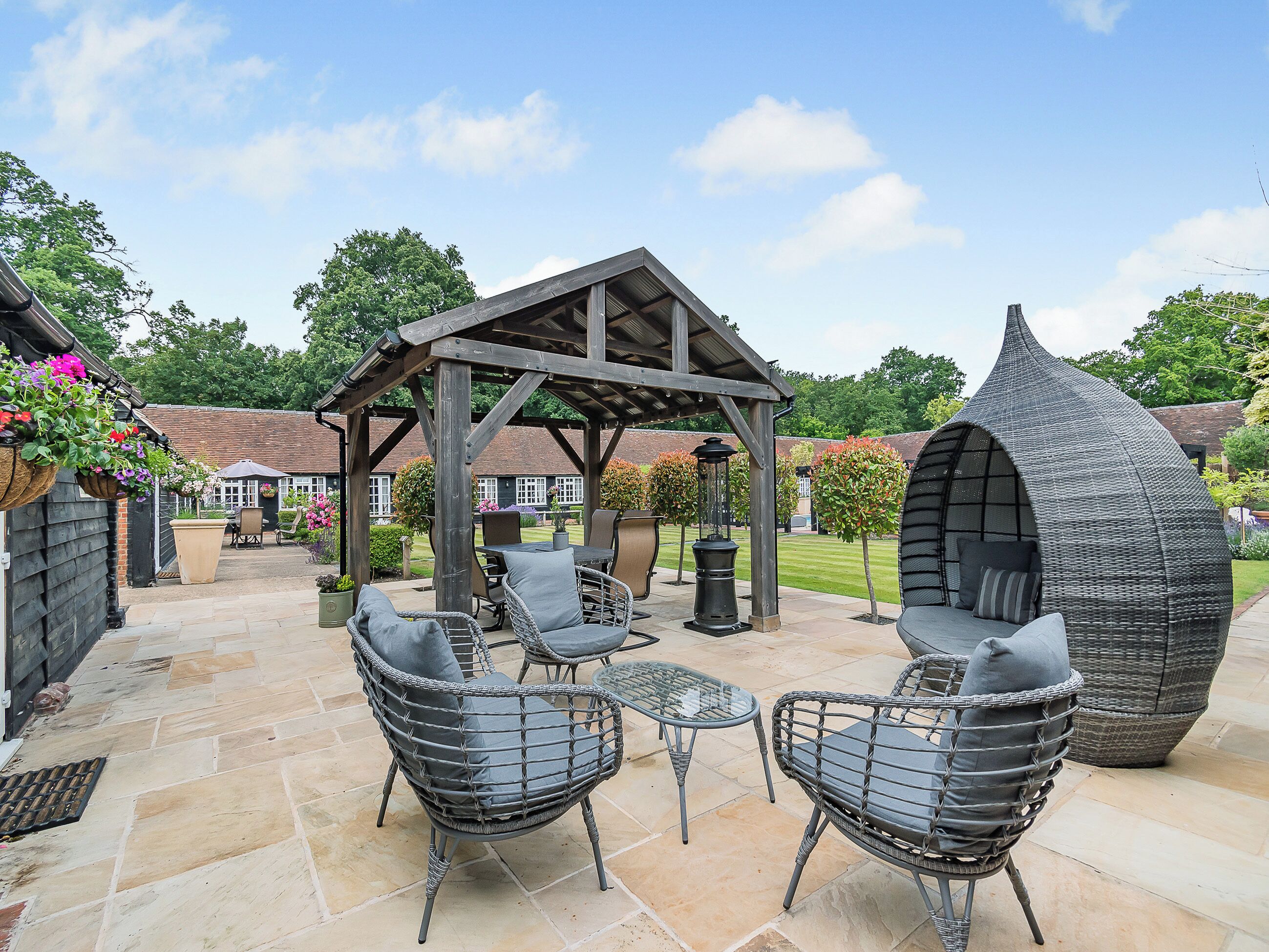 Un patio exterior con mobiliario de mimbre, una pérgola y una zona de estar esférica peculiar.