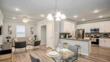 Una cocina moderna con armarios blancos, electrodomésticos de acero inoxidable y una isla central.