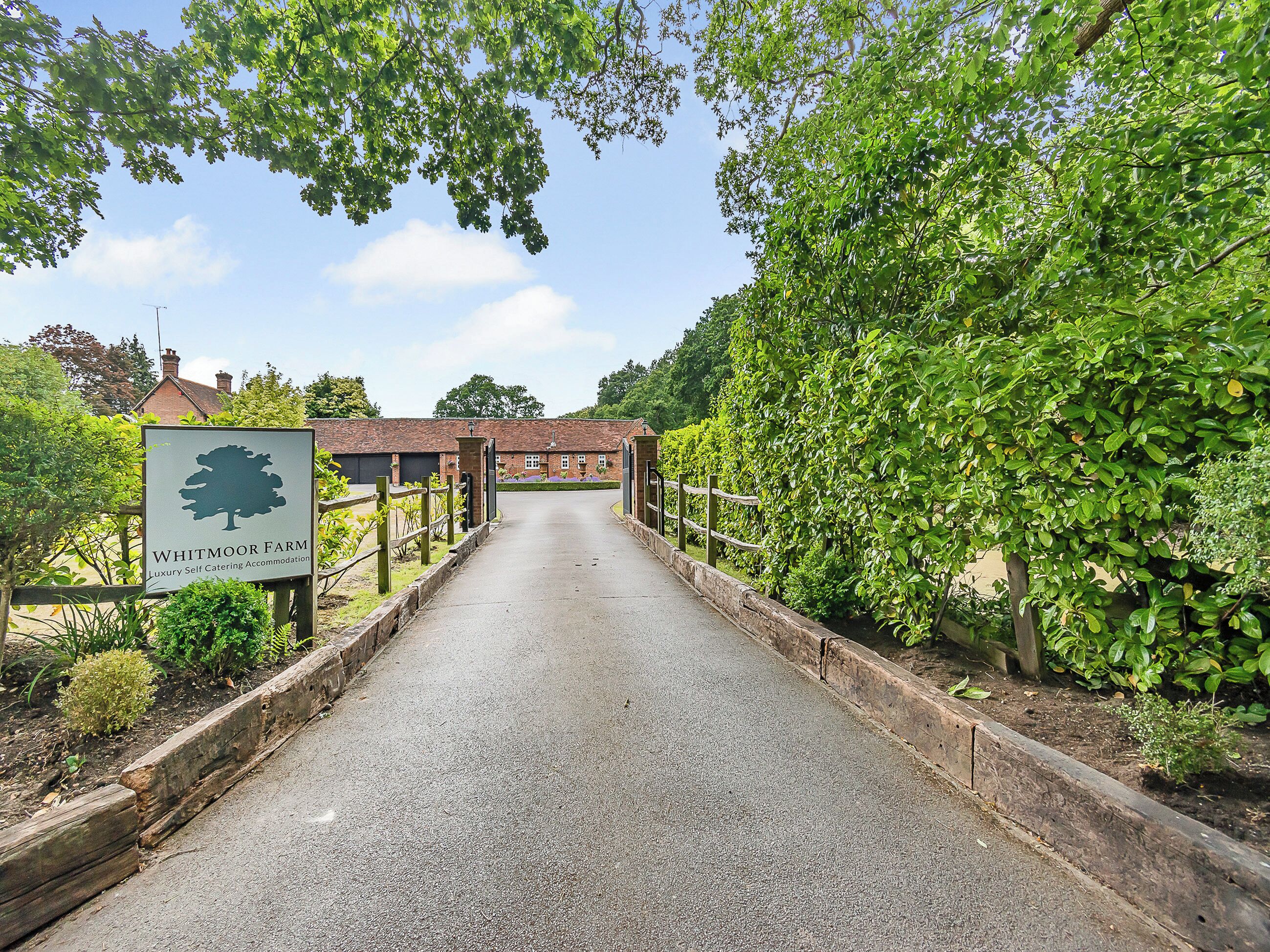 A pathway leading to a building with a sign indicating 'Whitmoor Farm Luxury Self Catering Accommodation.'