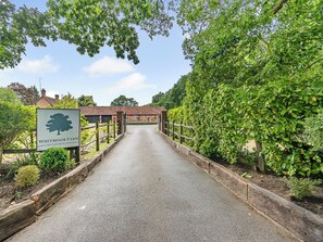 Un chemin menant à un bâtiment sur lequel est apposée une enseigne indiquant : « Whitmoor Farm, hébergement de luxe en formule location ».