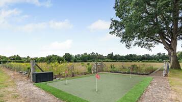 A miniature golf course with a green artificial turf, a flag, and a wooden structure.