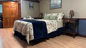 A bedroom with a wooden bed, a nightstand, a lamp, and a framed picture on the wall. - Meadowlark Suite at Cooperstown Lodge 3Miles toCDP (Cooperstown)