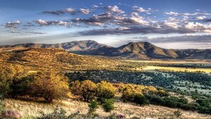 A mountainous landscape with a valley and scattered trees.