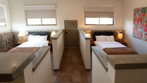 A hotel room with two beds, a stone wall, and a small hallway.