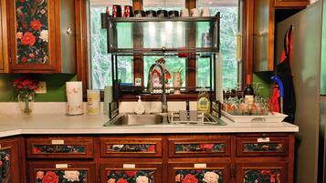 A kitchen with wooden cabinets, a stainless steel sink, and a window with a view of greenery.