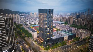 Un edificio de gran altura con fachada de vidrio moderna, rodeado de otros edificios altos y un entorno urbano cuidado.