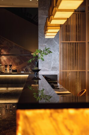 A modern reception area with a marble counter, a potted plant, and a wooden panel wall. - Jingxin SSAW Boutique Hotel (Hangzhou)