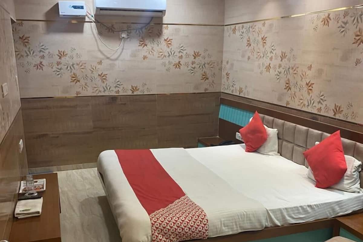 Una habitación de hotel con una cama, una mesita de noche, un cesto de basura y un equipo de aire acondicionado en la pared.