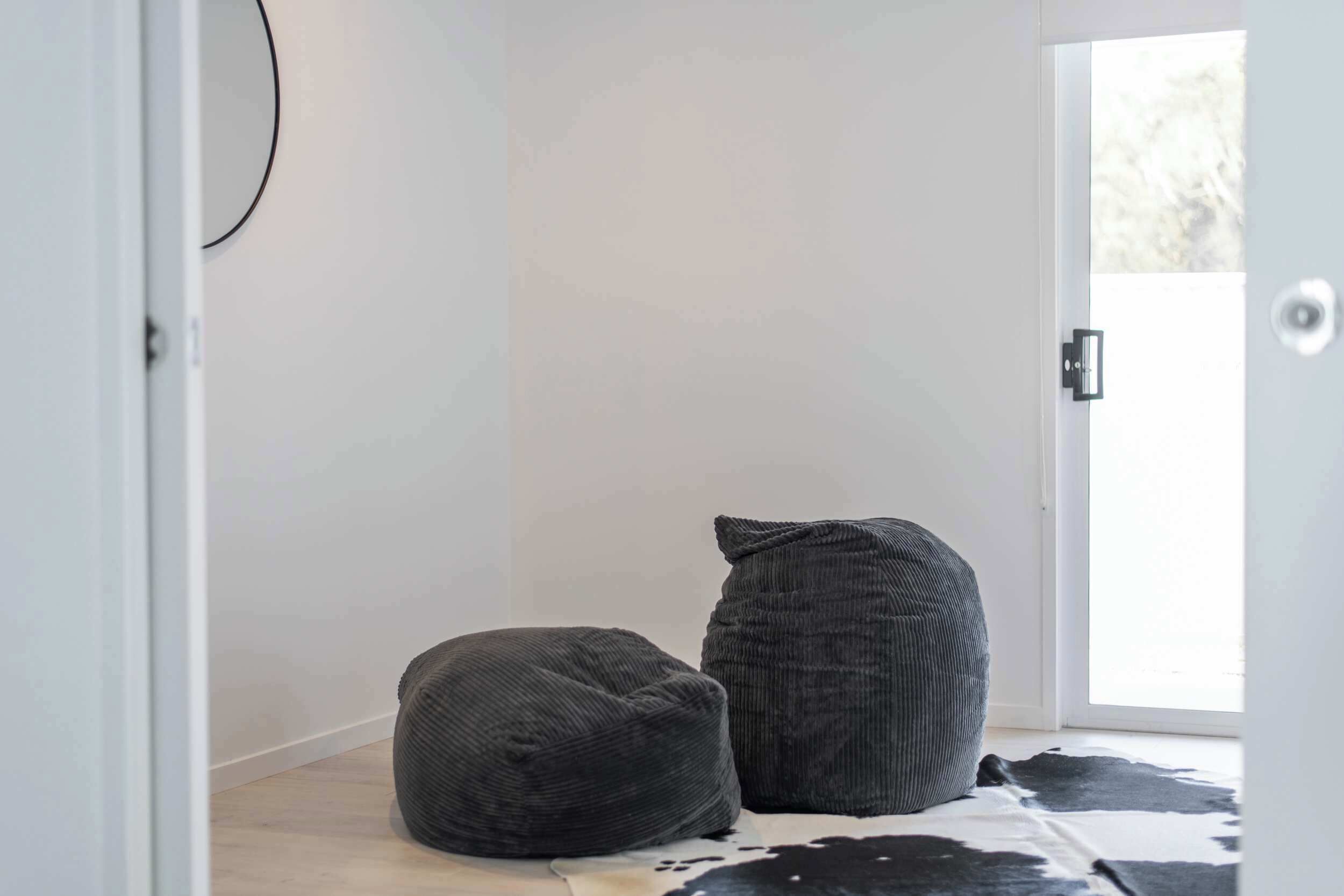 Una habitació amb una porta, dos seients de bossa i un moqueta de pell de vaca.