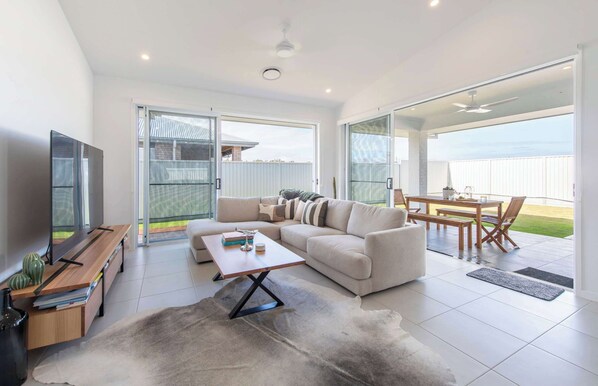 Un salón moderno con sofá, mesa de centro, televisor y vistas al exterior.