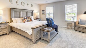 A bedroom with a bed, nightstands, a bench, a chair, and a window.