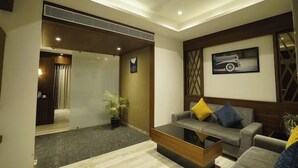 A modern living room with a sofa, coffee table, and a ceiling light fixture. - Mantra A Boutique Hotel (Jodhpur)