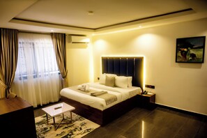 Una habitación de hotel moderna con una cama grande, una mesita de noche y un pequeño escritorio.