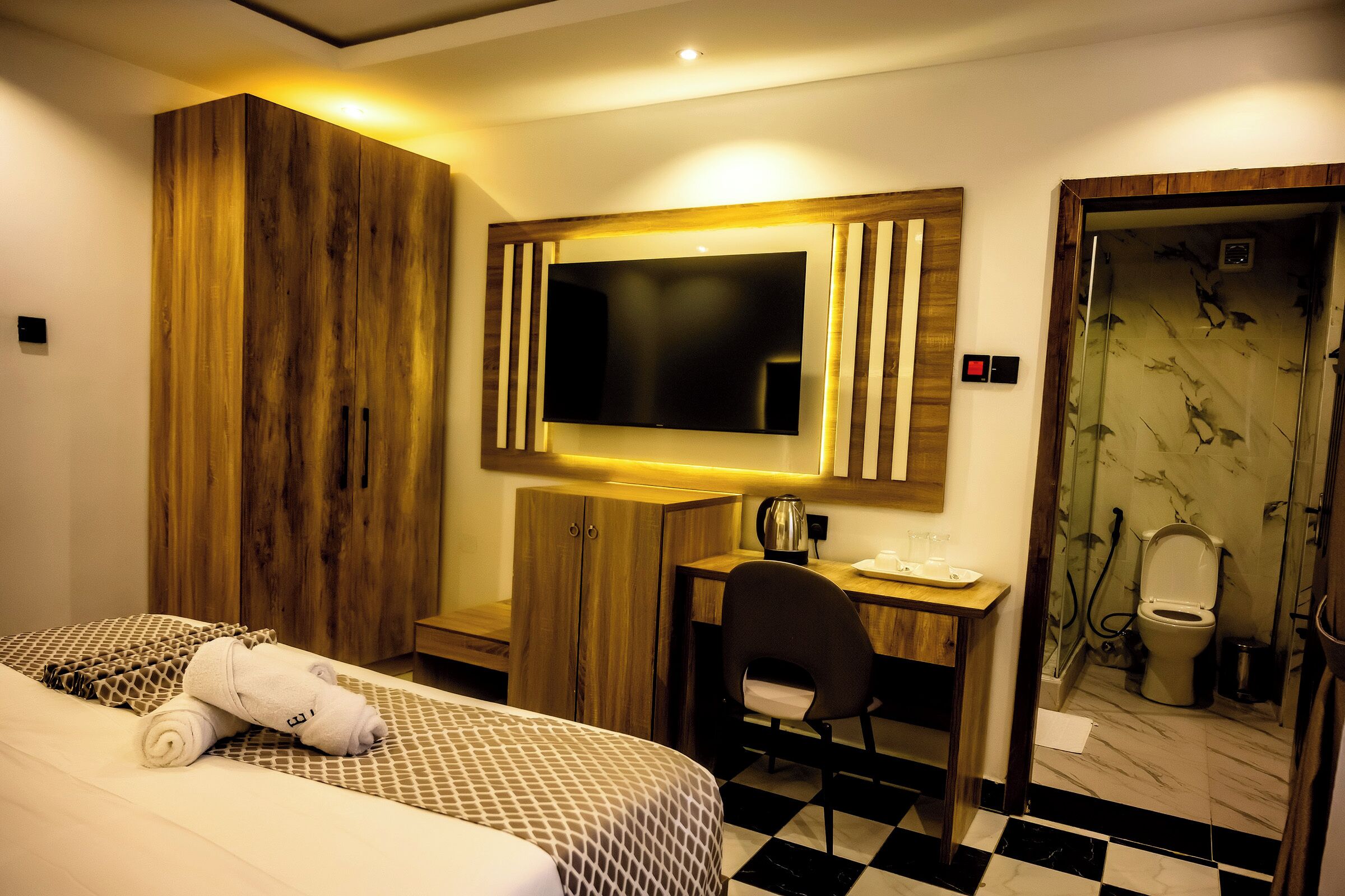 Una habitación de hotel con cama, escritorio, silla, televisión y baño.