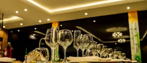 A restaurant setting with multiple tables set for dining, featuring wine glasses and cutlery.