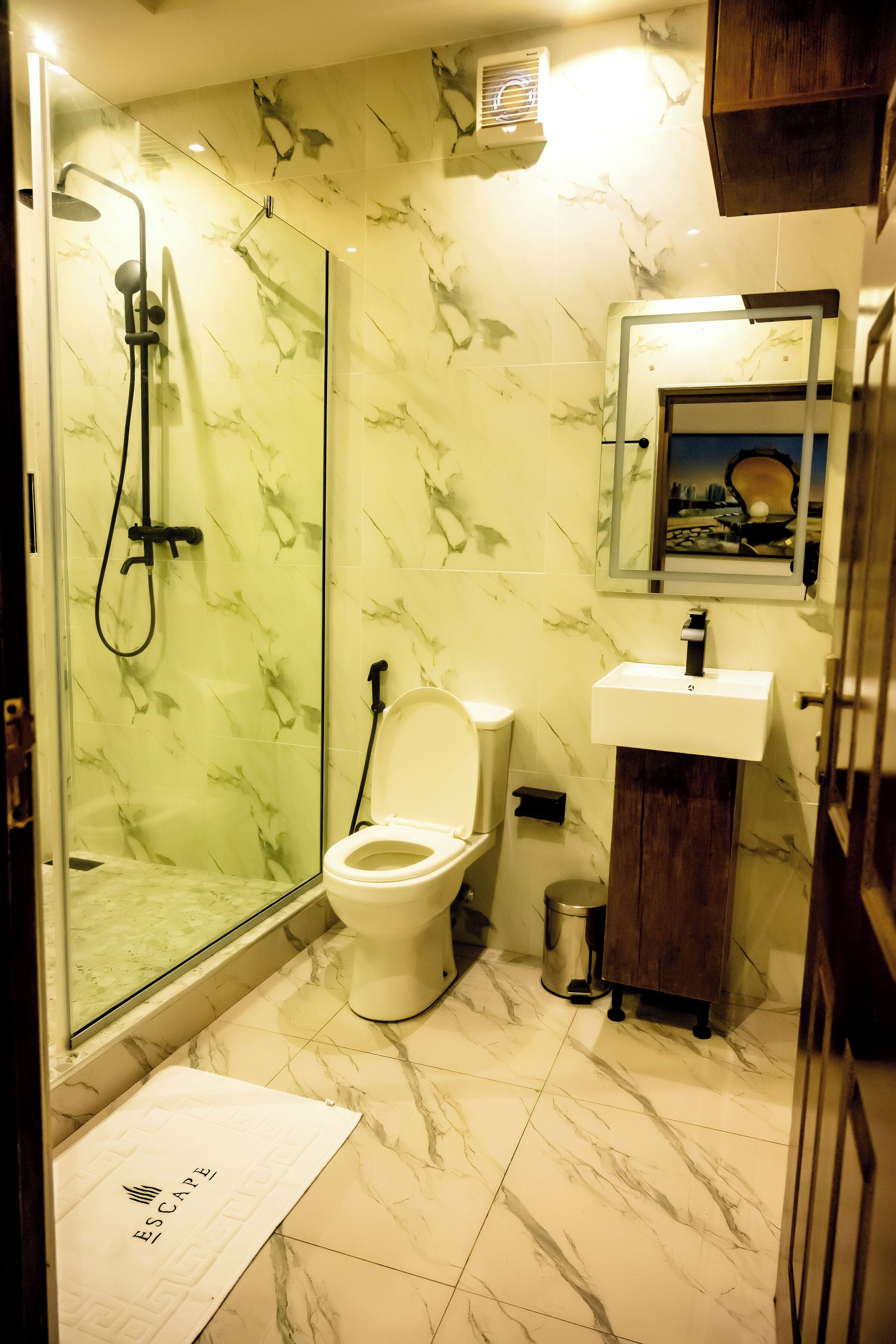 A bathroom with a shower, toilet, sink, and a mirror.
