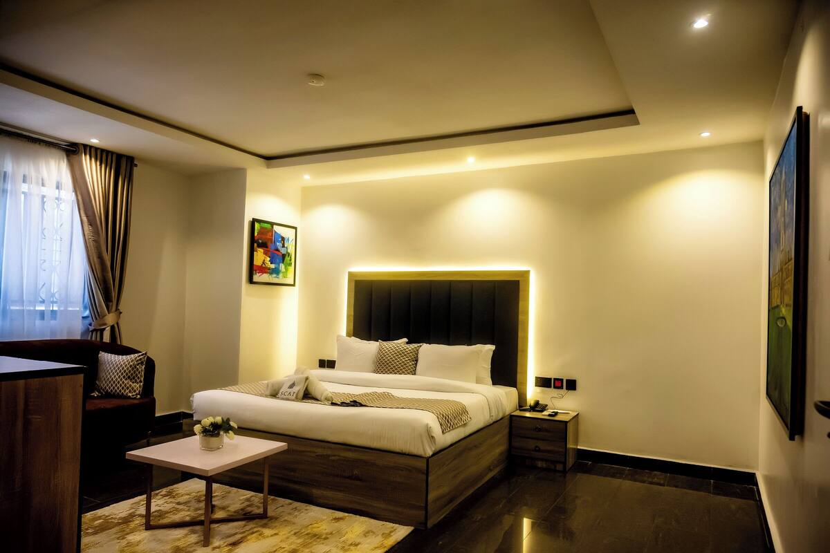 A modern bedroom with a large bed, bedside tables, a desk, and a sofa.