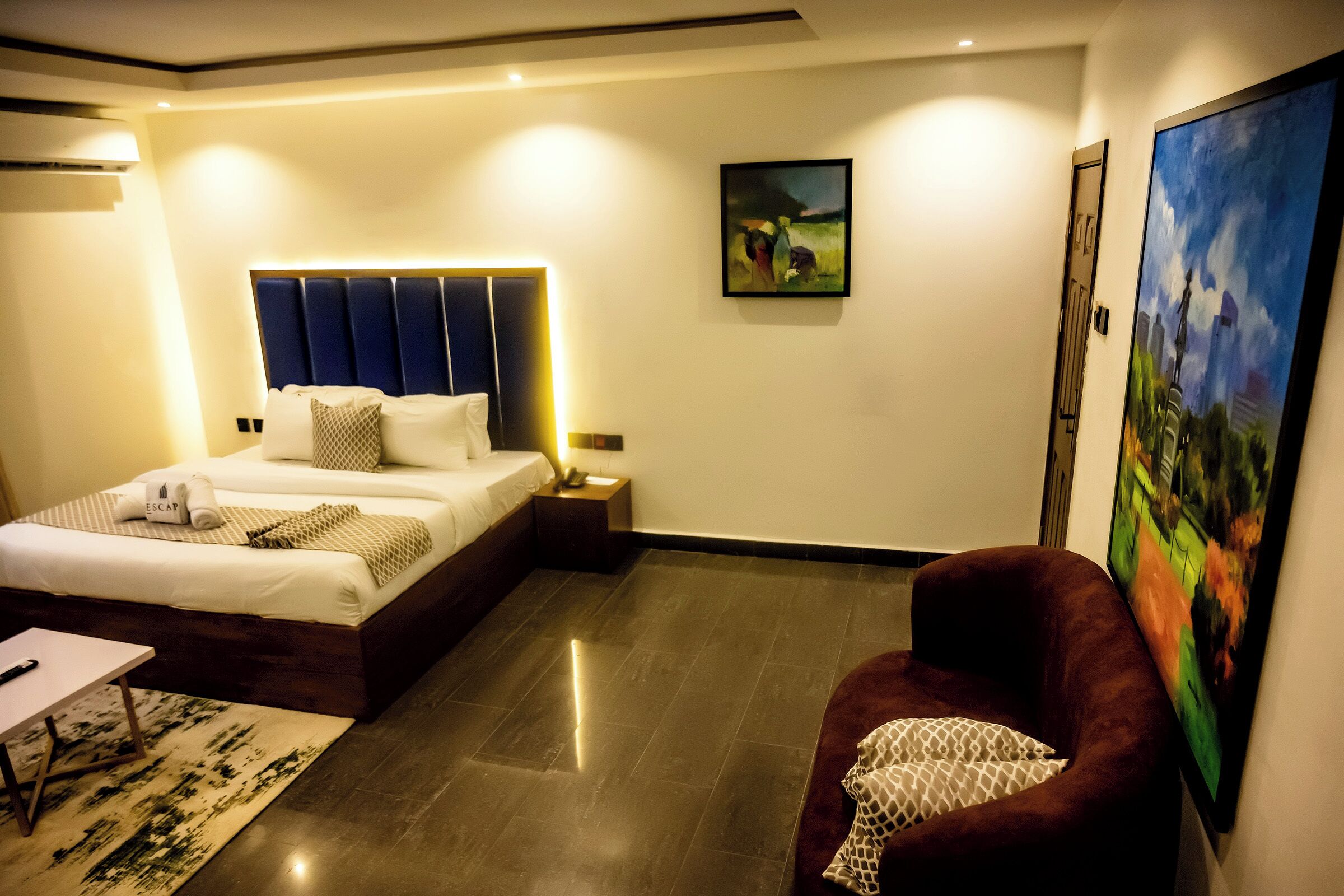 Een moderne hotelkamer met een groot bed, een bureau, een stoel en een schilderij aan de muur.