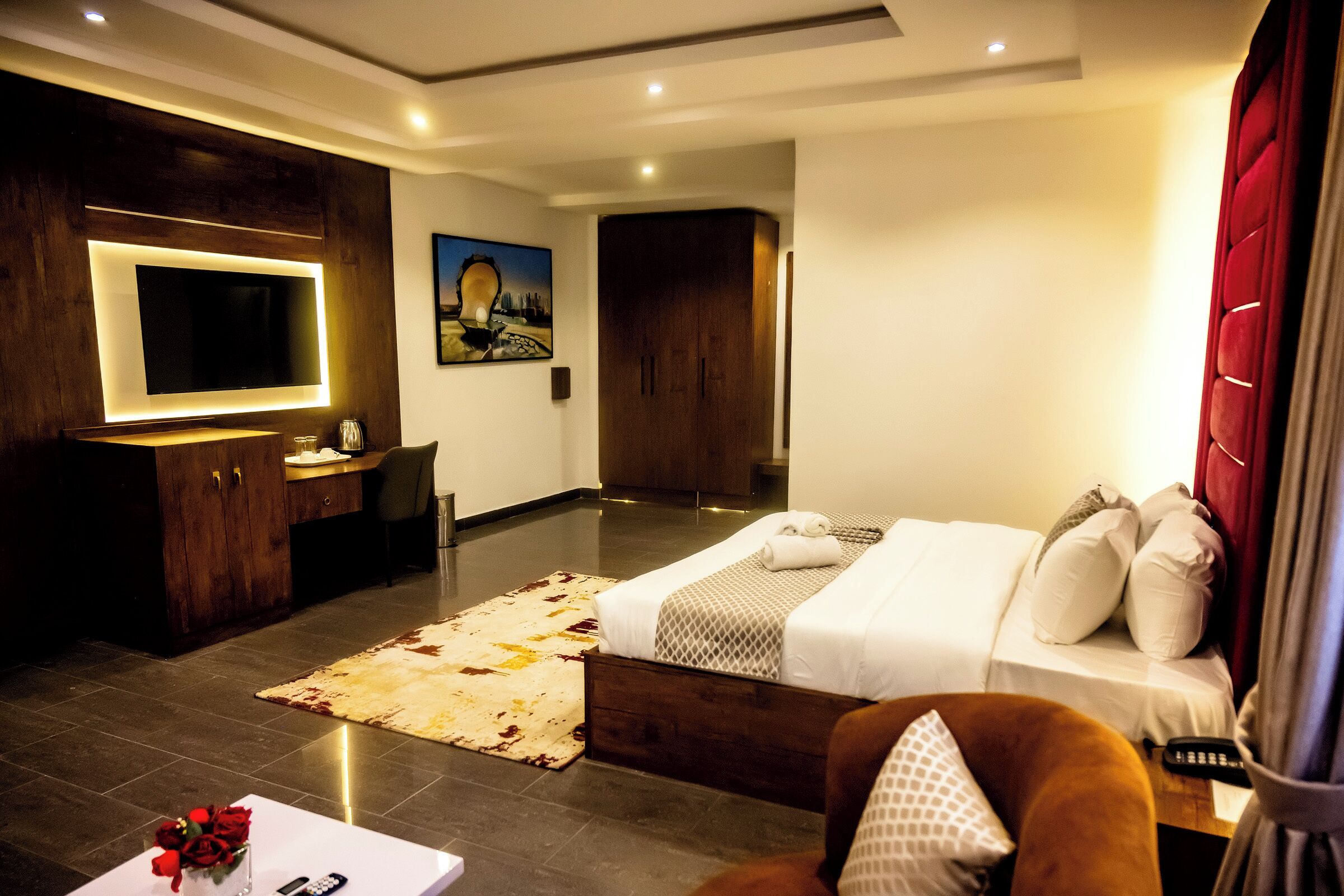 Ein modernes Hotelzimmer mit einem großen Bett, einem Schreibtisch, einem Flachbildfernseher und einem Bild an der Wand.