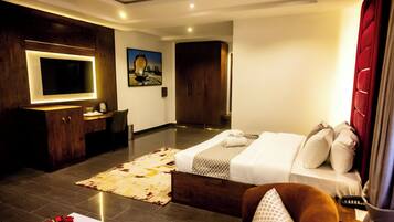 Una habitación de hotel moderna con una cama grande, un escritorio, un televisor de pantalla plana y un cuadro en la pared.