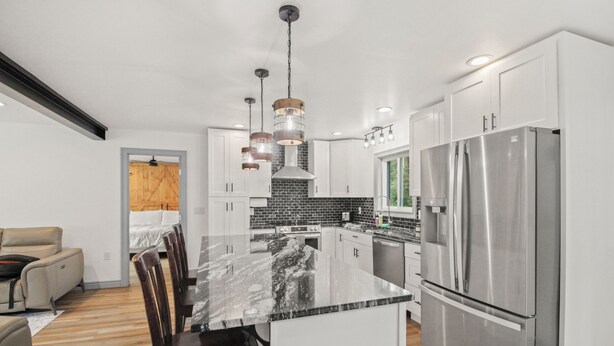 A modern kitchen with white cabinets, a large island, stainless steel appliances, and pendant lighting. - Comfortable Cottage with hot tub in Delta Junction, AK (Delta Junction)