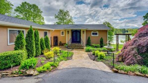 A two-story house with a stone pathway leading to a dark blue front door, surrounded by well-maintained landscaping and a clear sky. - Lake Chatuge Home: Boat Dock, Hot Tub & Perks! (Hayesville)