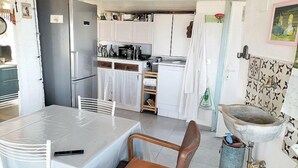 Una cocina compacta con armarios blancos, un refrigerador y un lavamanos.