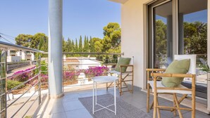 Un balcon avec deux chaises, une petite table et une vue sur un quartier résidentiel, avec des arbres et des immeubles.